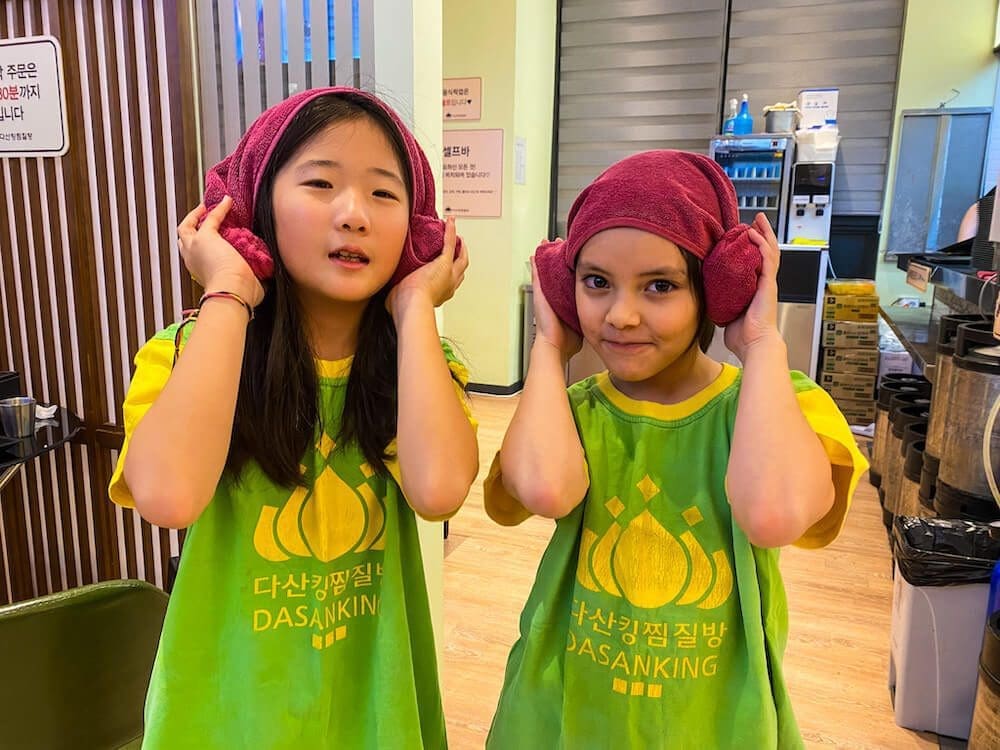 kids wearing a Korean sauna uniform and a traditional lamb head towel roll, known as yang meori.
